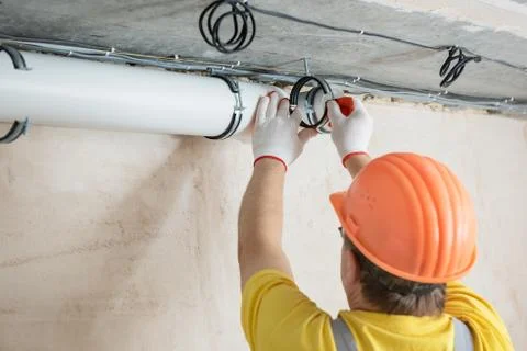 The worker is installing a ventilation system. Stock Photos