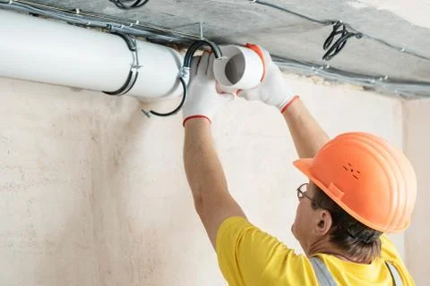 The worker is installing a ventilation system. Stock Photos