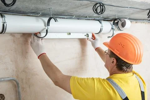 The worker is installing a ventilation system. Stock Photos