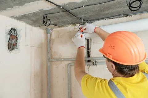 The worker is installing a ventilation system. Stock Photos