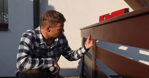 Worker installing wooden balcony railing with screwdriver during house cons.. Stock Footage 344873614