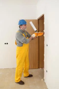 Worker installing wooden door, using polyurethane foam Stockfoto's