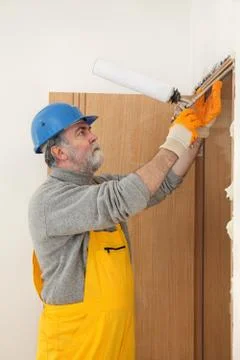 Worker installing wooden door, using polyurethane foam Stock Photos