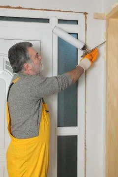 Worker installing wooden door, using polyurethane foam Stock Photos