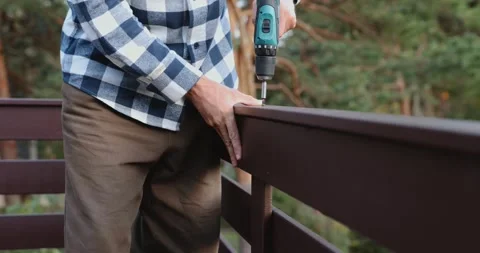 Worker installing wooden patio railing with screwdriver during house constr.. Stock Footage 344873616
