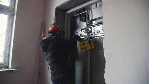 Worker installs electric equipment of elevator in building Stock Footage 198768251