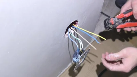 Worker installs electrical outlet in wall with various wires at construction sit Stock Footage 326697048