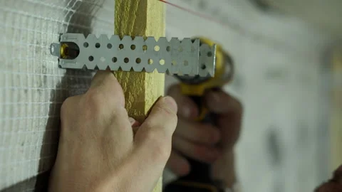 A worker installs a frame of beams and metal fasteners for installing OSB Stock Footage 249752876