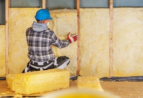 Worker installs insulation in a building during a renovation project Stock Photos