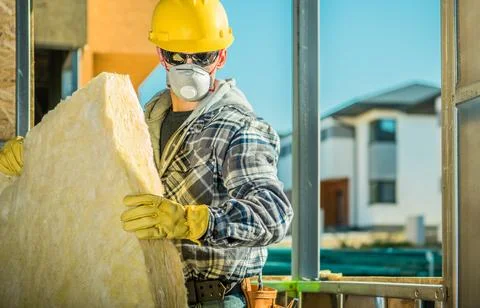 Worker Installs Insulation at Construction Site in Sunlight Foto stock