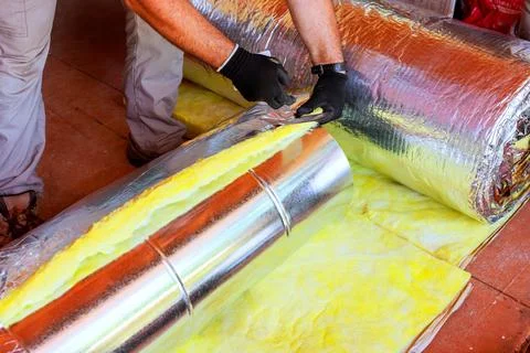 Worker installs insulation in duct pipe construction project Stock Photos