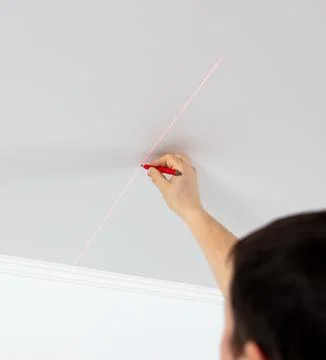 A worker installs a light bulb in a stretch ceiling Stock Photos