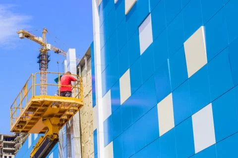 A worker installs panels facing on the facade of the house Stock Photos