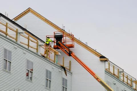 A worker installs panels siding on the facade of the house Stock Photos