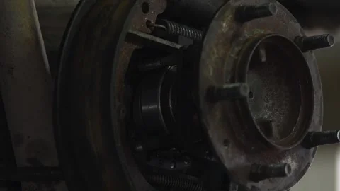 Worker installs rusty metal wheel hub component back on car Stock Footage 344231587
