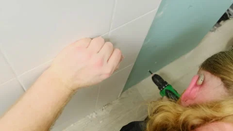 Worker installs screw into plasterboard using electric screwdriver Stock Footage 304407978