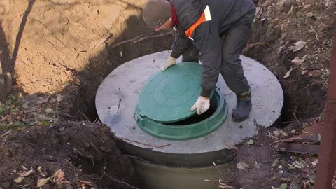 A worker installs a sewer manhole on a septic tank made of concrete rings Stock Footage 165410341