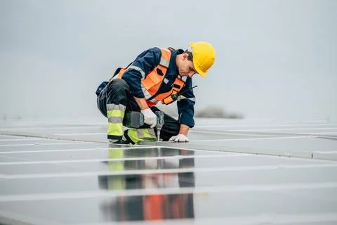 Worker installs solar panels on a cloudy day at a renewable energy installa.. Foto stock