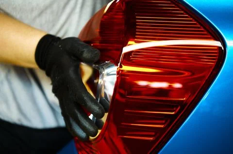 Worker installs tail light of new car in assembling workshop Stock Photos