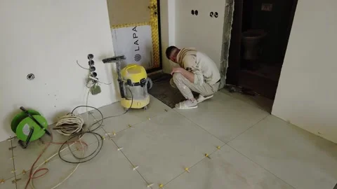 Worker installs tiles in a bathroom area while preparing for finishing touches i Stock-Footage 332365375