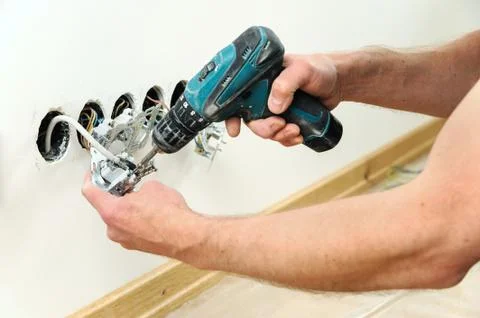 Worker installs a TV wall socket. Stock Photos