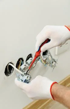 Worker installs a TV wall socket. Stock Photos