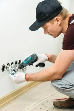 Worker installs a TV wall socket. Stock Photos