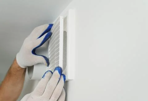 Worker installs ventilation grille. Stock Photos