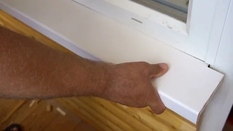 A worker installs a window sill in the loggia 動画素材 77828580