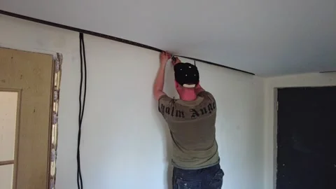 Worker installs wiring along the wall in a room in a house in the afternoon Stock-Footage 332563151