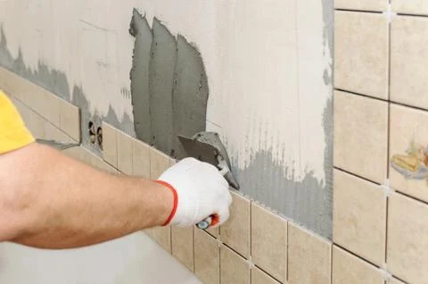 Worker instiling tiles on the wall in the kitchen. Stock Photos