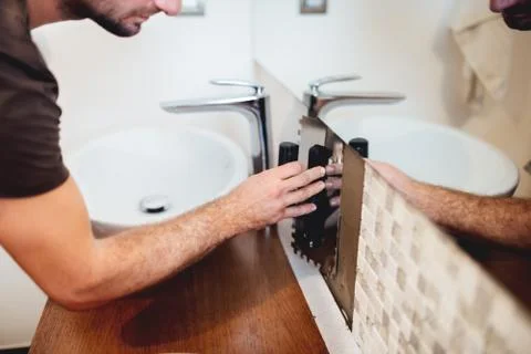 Worker intalling mosaic tiles and using industrial trowel in modern bathroom Stock Photos