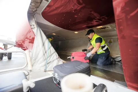 Worker Kneeling While Unloading Airplane Foto stock