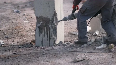 A worker knocks concrete off piles with a hammer drill. Stock Footage 164889423