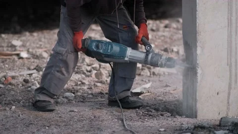 A worker knocks concrete off piles with a hammer drill. Video stock 164890617