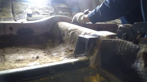 Worker knocks old mastics off bottom of car with a chisel and a hammer Stock Footage 127530084