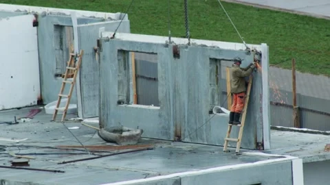 Worker On Ladder Uses Grinder On Concrete Wall. Sparks Fly During Prefabricated Stock Footage 323913036