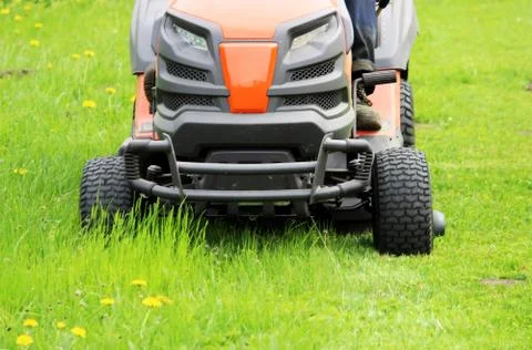 Worker at a lawnmower mowing grass on a platform in front of the Gatchina Stock Photos