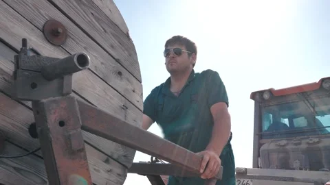 Worker lay the cable in the ground with a large wheeled tractor Stock Footage 248070528