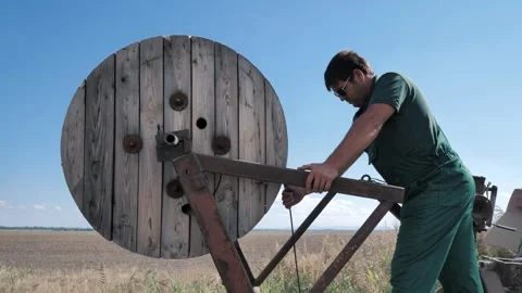 Worker lay the cable in the ground with a large wheeled tractor Stock Footage 248076100