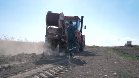 Worker lay the fiber optic cable in the ground with a large wheeled tractor Stock Footage 248524744
