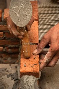 Worker laying brick wall with cement Stock Photos