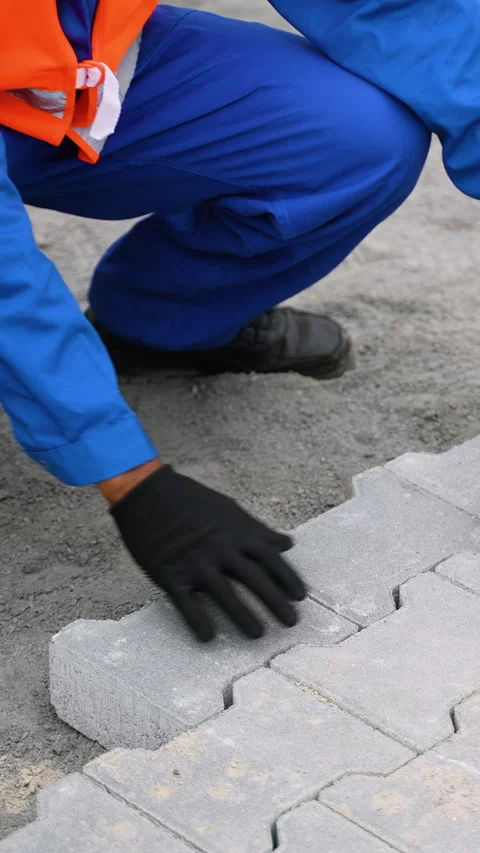 Worker laying interlocking paving stones on a construction site Stock Footage 300895142
