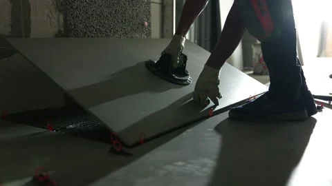 Worker laying large floor tile using vacuum suction cup Stock Footage 344471974