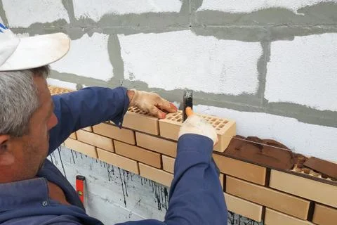 The worker is laying the masonry of the front brick in the village. Fotos de archivo