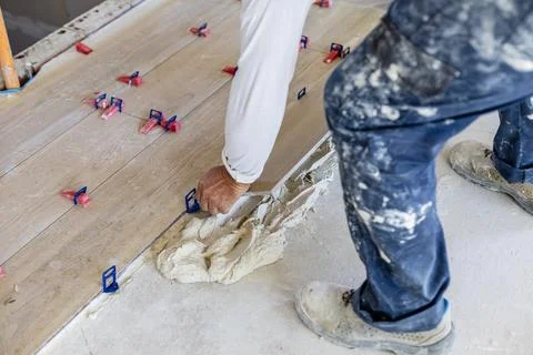 Worker laying new tile flooring during home renovation Stock Photos