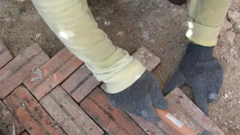 Worker laying red brick  pathway around the house Stock Footage 255350000