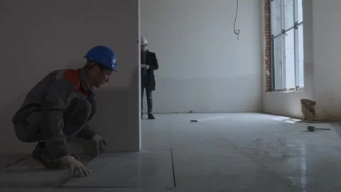 Worker laying tiles. Engineers are discussing the construction plan Stock Footage 321004550