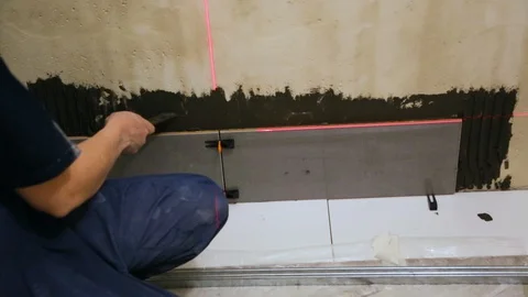 Worker laying tiles on the wall 库存影片 128411147