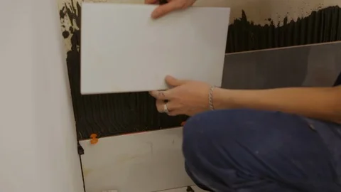 Worker laying tiles on the wall Видео 128412211